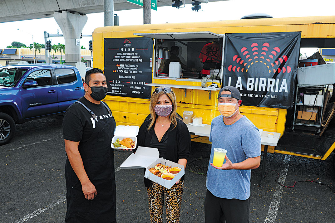 La Birria Tacos executive chef and co-owner Arturo Silva (left) and co-owner Justin Mizufuka (right), as well as Anne Lee, hold up the food truck’s famous dishes.
